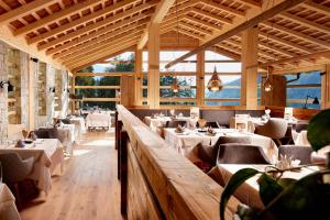 a restaurant with white tables and chairs and windows at Cyprianerhof Dolomit Resort in Tires