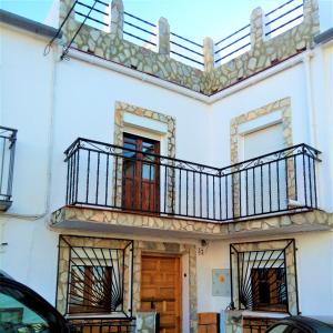 un edificio blanco con 2 balcones y una puerta en La Villa, en El Burgo