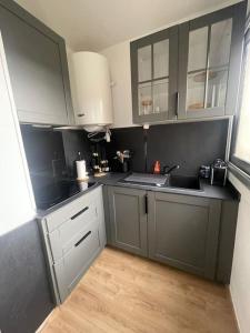 a kitchen with gray and white cabinets and a wooden floor at Studio moderne à Antony in Antony