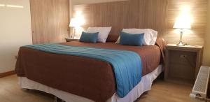 a hotel room with a large bed with blue pillows at Hotel D&V Concepción in Concepción