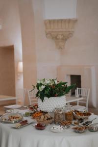 una mesa con platos de comida y un jarrón de flores en Relais Monastero Santa Teresa - Albergo Diffuso, en Nardò