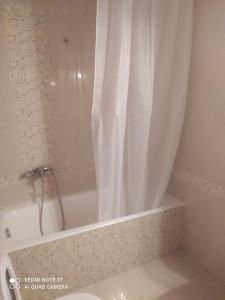 uma casa de banho com banheira e cortina de chuveiro em Family House em Agios Nikolaos