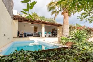 a swimming pool in front of a house with a palm tree at Can Cosset Holiday Home in Capdepera
