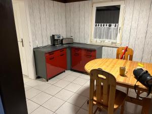 a kitchen with a wooden table and red cabinets at Zwei Eichen Gadenstedt in Ilsede