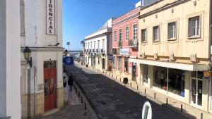 een straat met gebouwen en mensen die over een straat lopen bij Palacete da Baixa by MY CHOICE in Faro