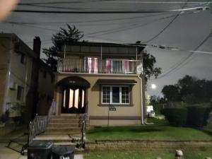 a house with a porch and a balcony at Cozy Studio; Lower Level Unit in Laurelton