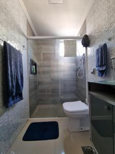 a bathroom with a toilet and a shower with blue towels at Apartamento Classe A in Praia Grande
