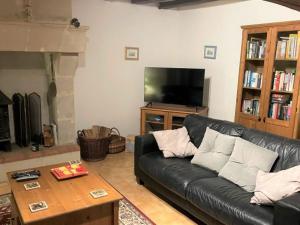 a living room with a black leather couch and a tv at La Maison Tournesol - 3 bedroom house with large garden near Saumur in Saint-Martin-de-la-Place