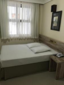 1 dormitorio con 1 cama grande y ventana en Hotel Estação Express, en Curitiba