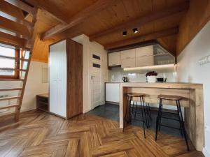a kitchen with wooden floors and a counter with stools at Smrekowe Zacisze in Bańska Niżna