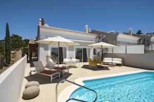 a swimming pool with chairs and umbrellas next to a house at 401 Villa Salemar in Salema