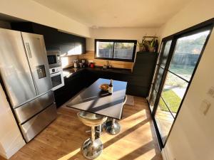 eine Küche mit Tisch und Edelstahlkühlschrank in der Unterkunft Les cabanes de l'océan, Villa confort proche plage sauvage in Messanges