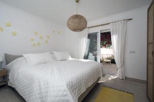a white bedroom with a bed and a window at 401 Villa Salemar in Salema +15 photos
