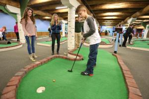 a boy playing golf in a miniature golf course at Seven Springs 1 Bedroom Premium Condo, Ski In Ski Out condo in Champion