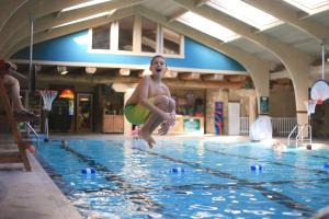 a young boy jumping into a swimming pool at Seven Springs 1 Bedroom Premium Condo, Ski In Ski Out condo in Champion