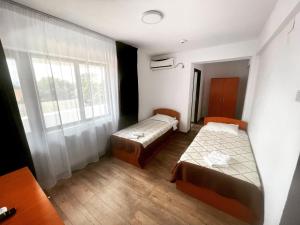 Habitación pequeña con 2 camas y ventana en Hotel Tata Si Fii en Bechet