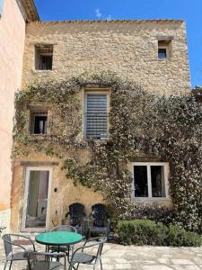 a table and chairs in front of a building at Gîte Le Nathalie Meublé de tourisme 4 étoiles Le Moulin de Prédelles in Reillanne