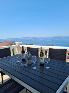 una mesa con botellas de vino y copas en el balcón en Apartments Tonia br. 1 en Zavalatica