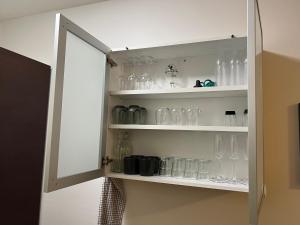 a cupboard filled with glasses and bottles at Modern 45m^2 Ullanlinna apartment in Helsinki