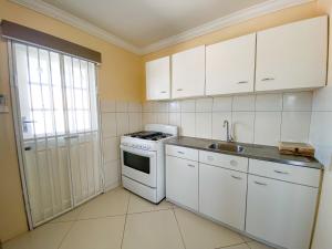 una cucina con armadi bianchi, piano cottura e lavandino di Benito Home a Tera Kora