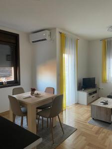 a living room with a table and chairs and a television at Apartman Arcobaleno in Vrnjačka Banja