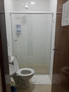 a bathroom with a toilet and a glass shower at Pousada Acqua Infinity PISCINA CLIMATIZADA PÉ NA AREIA in Bertioga +45 photos