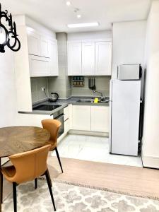 a kitchen with white cabinets and a table and a refrigerator at The Trust Highvill Ishim D in Astana