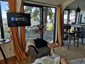 une personne assise sur une chaise dans un salon avec une télévision dans l'établissement lodge-bélvédere sur les hauteurs de vichy, à Vichy