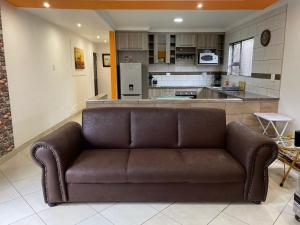 a brown couch in a living room with a kitchen at Cozy Inn in Tikoe