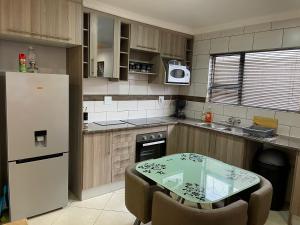 a kitchen with a table and a white refrigerator at Cozy Inn in Tikoe