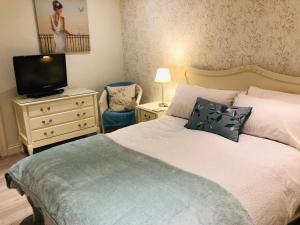 a bedroom with a bed with a television and a dresser at Squirrel house B&B in High Wycombe