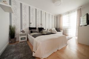 ein weißes Schlafzimmer mit einem großen Bett und einem TV in der Unterkunft GDE Holló Apartments in Budapest