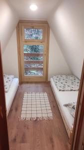 a attic room with two beds and a window at Holiday Home Mreznica in Gornji Zvečaj