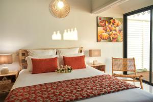 ein Schlafzimmer mit einem großen Bett mit roten Kissen in der Unterkunft LES GALETS ROUGES LODGES & SPA in Bouillante