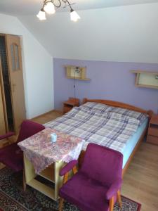 Schlafzimmer mit einem Bett und einem Tisch mit lila Stühlen in der Unterkunft Pokoje Panorama in Wysowa-Zdrój