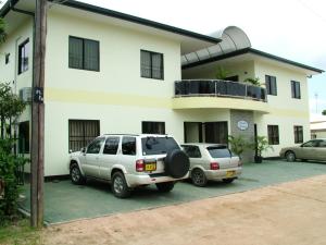 two cars parked in a parking lot in front of a house at Rachel's Apartments in Paramaribo