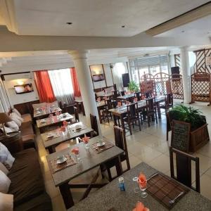 - un restaurant avec des tables et des chaises dans une salle dans l'établissement Hotel Le Relais Normand, à Antananarivo