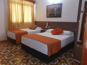 Cette chambre d'hôtel comprend 2 lits avec des draps orange. dans l'établissement Hotel Boutique el Sol, à Cartago