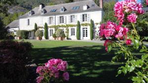 una gran casa blanca con flores rosas en el patio en Domaine de Monda, en Argelès-Gazost