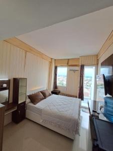 a bedroom with a bed and a tv and windows at Paradise Room By Vivo Apartment in Seturan