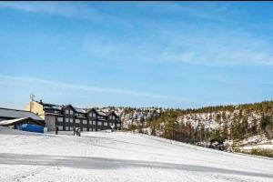 un rifugio da sci su una collina innevata con un edificio di Topp Leilighet ski inn ski out Gautefall a Drangedal