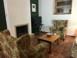 sala de estar con 2 sillas, mesa y TV en La Almedina casa Bellavista, en Cazorla