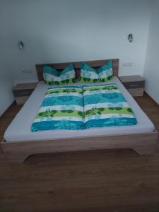 a bed with blue and green sheets and pillows at Appart Holzknecht in Längenfeld