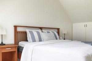 a bedroom with a large white bed with striped pillows at Mysigt hus med kamin och pool in Torekov