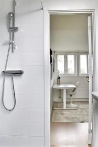 La salle de bains blanche est pourvue d'une douche et d'une table. dans l'établissement Mysigt hus med kamin och pool, à Torekov