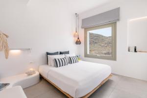 ein weißes Schlafzimmer mit einem Bett und einem Fenster in der Unterkunft My Castle House - MG Villas Mykonos in Fanari