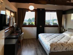 a bedroom with a bed and a desk and two windows at Heidi Bed and Breakfast in Albavilla