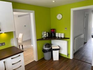 a kitchen with green walls and a counter with a trash can at Msquared Villa, Modern 3-Bedroom House, 3 Parking Spaces in Kidlington +23 photos