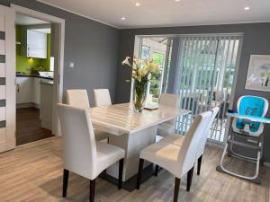 a dining room table with white chairs and a vase of flowers at Msquared Villa, Modern 3-Bedroom House, 3 Parking Spaces in Kidlington