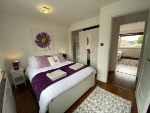 a bedroom with a bed with purple and white sheets at Msquared Villa, Modern 3-Bedroom House, 3 Parking Spaces in Kidlington
